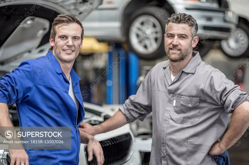 Two confident car mechanics in repair garage