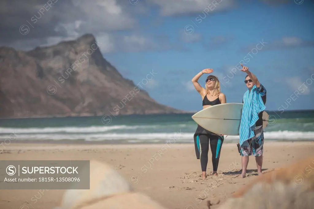 Teenage boy with down syndrome and woman with surfboard on beach