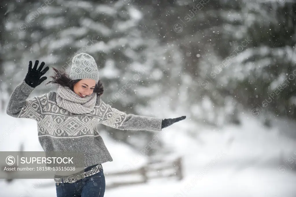 Happy woman wearing knitwear dancing in the snow