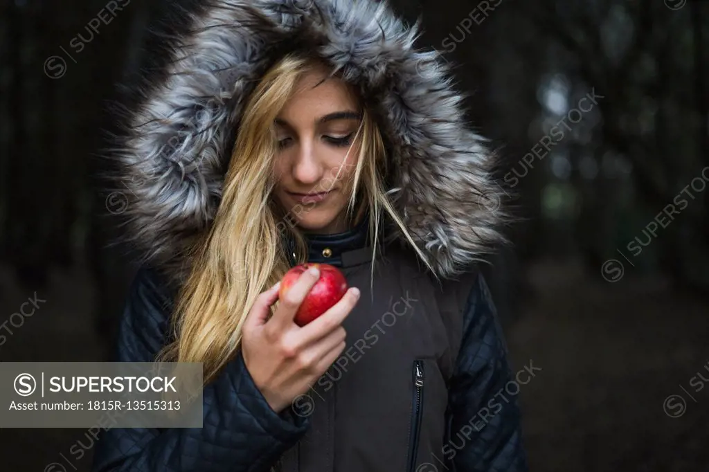 Young woman with red apple wearing hooded jacket