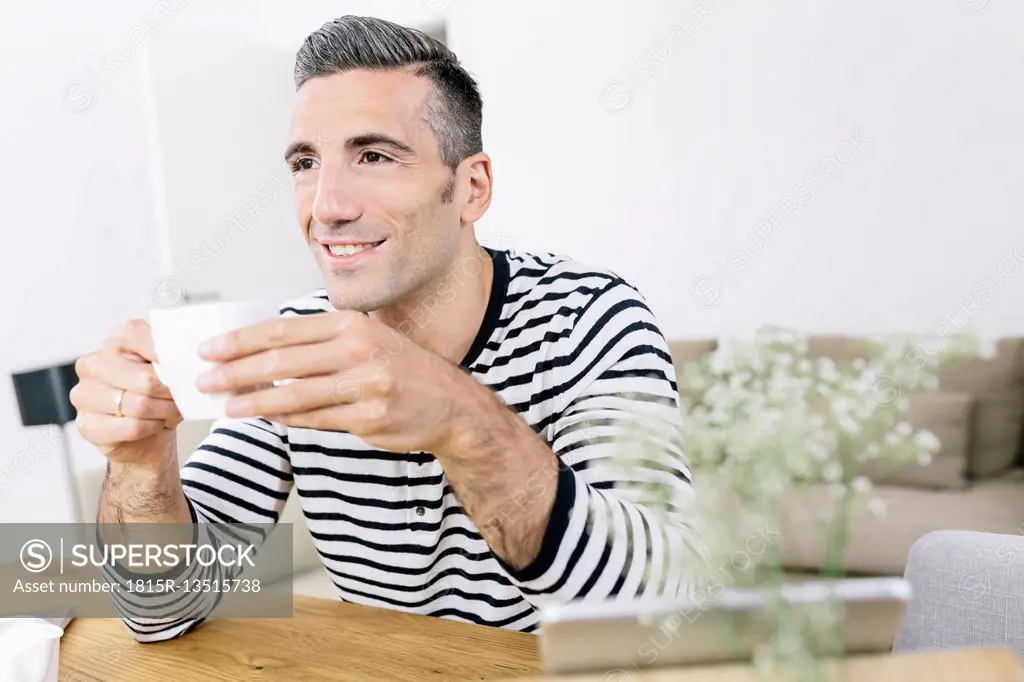 Smiling man at home holding coffee cup