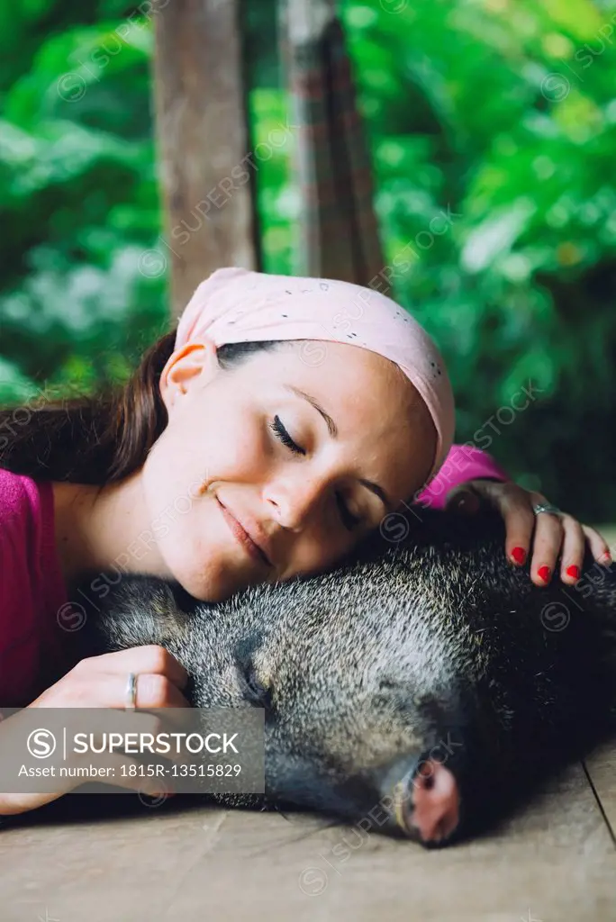 Peru, Woman cuddling domesticated peccary