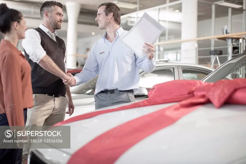 Car dealer shaking hands with man in car dealership