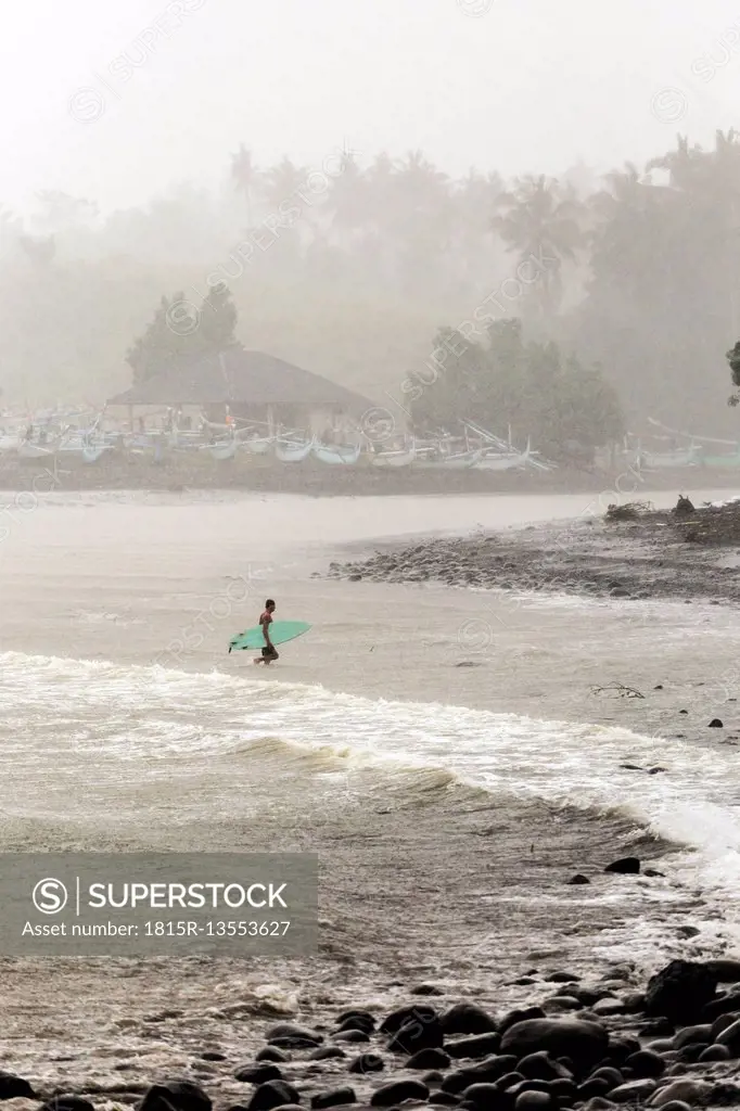 Indonesia, Bali, surfer carrying surfboards in the sea