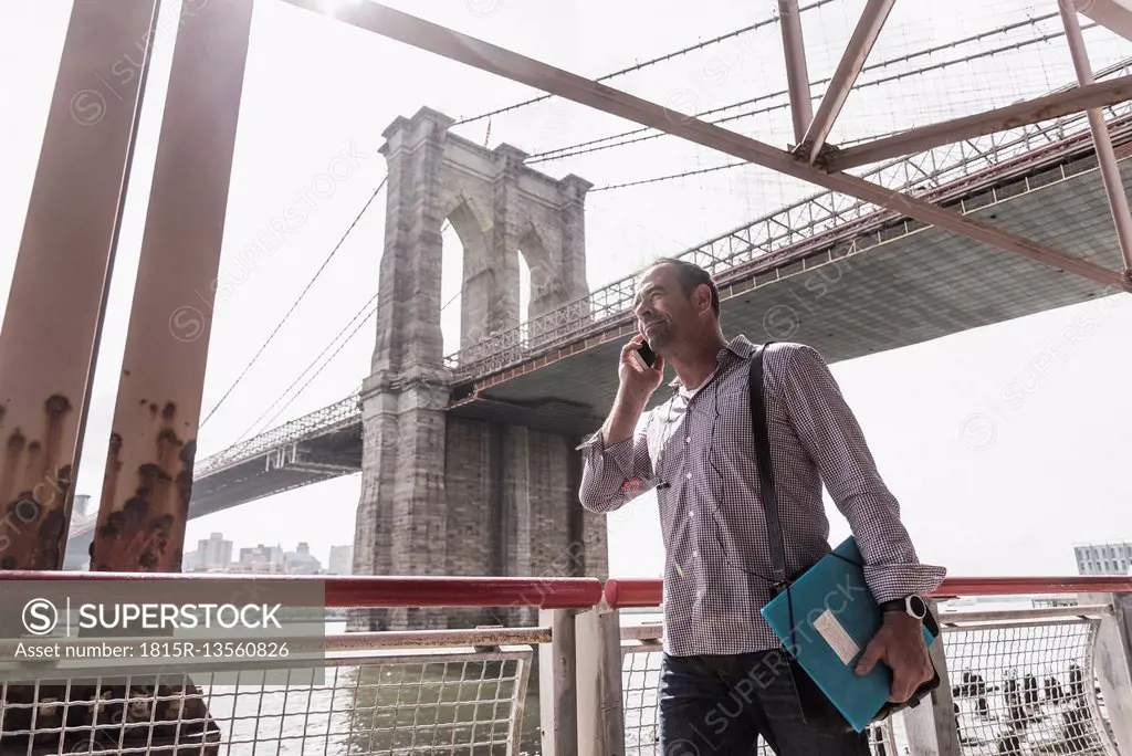 USA, New York City, man at East River talking on cell phone