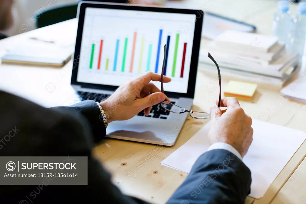 Businessman studying bar chart on laptop