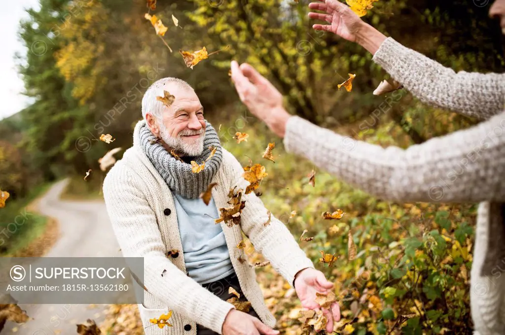 Happy senior man and his wife playing with autumn leaves