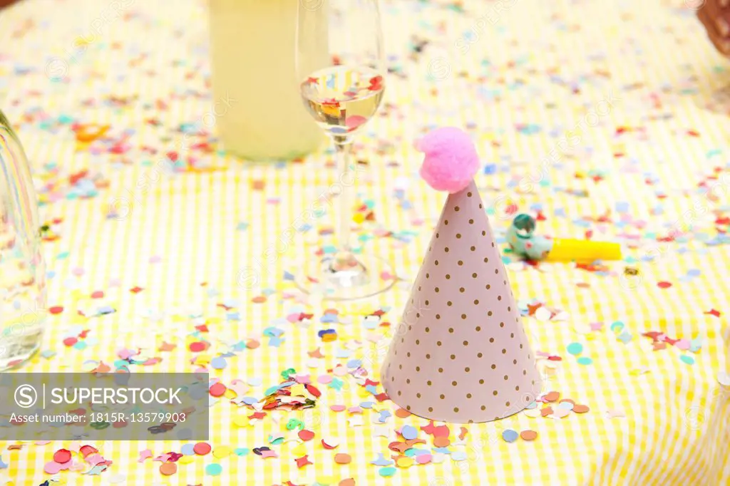 Party hat and party blower on table with confetti