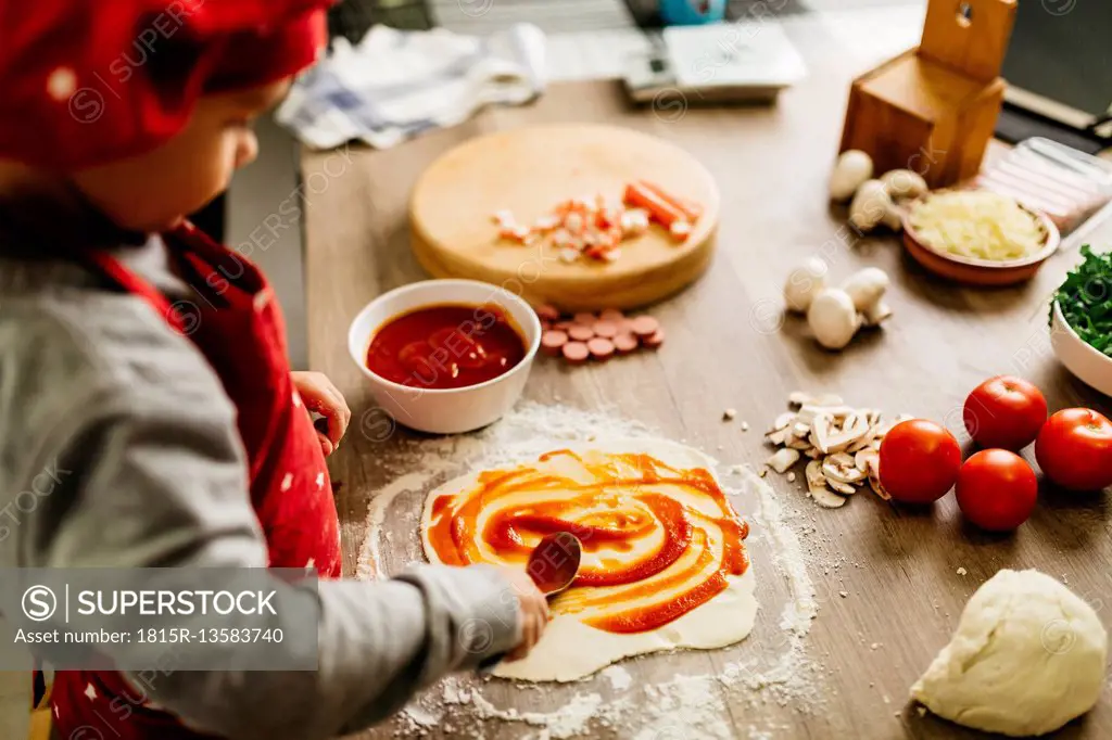 Little boy preparing pizza at home