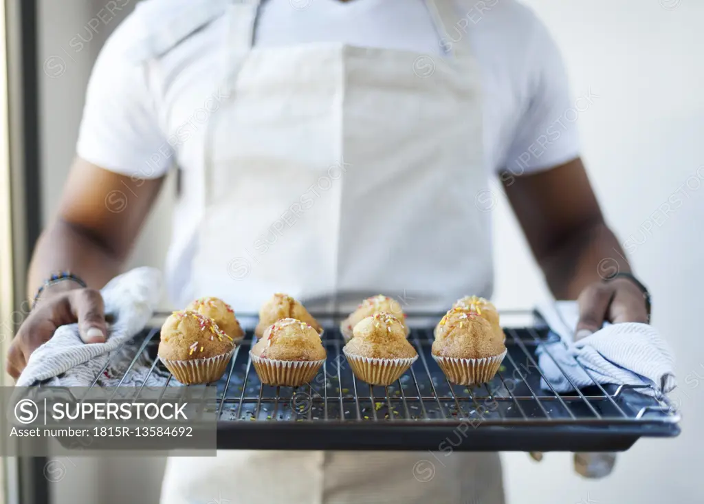 Man holding tray with muffins