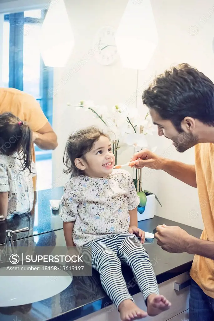 Father and daughter in bathroom brushing teeth