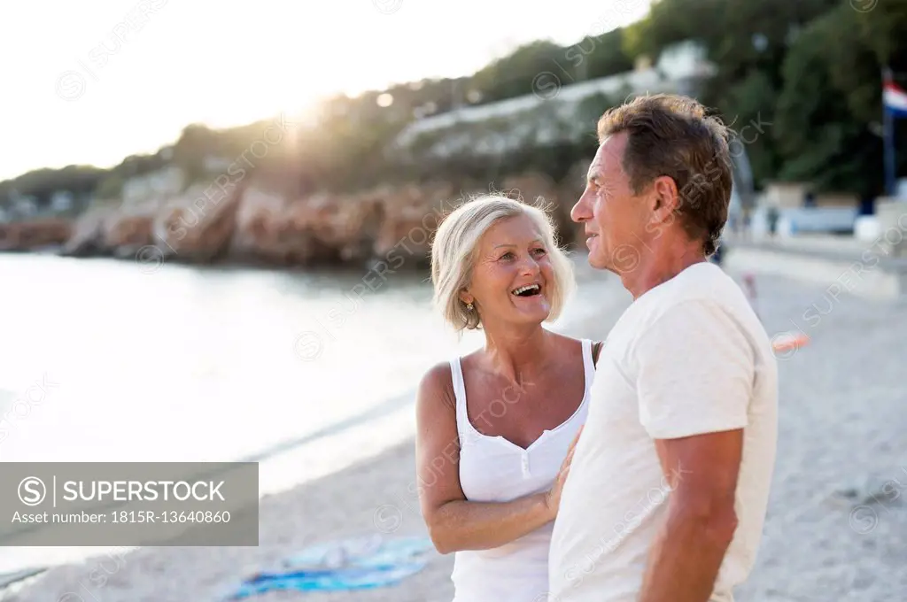 Senior couple relaxing on the beach at evening twilight