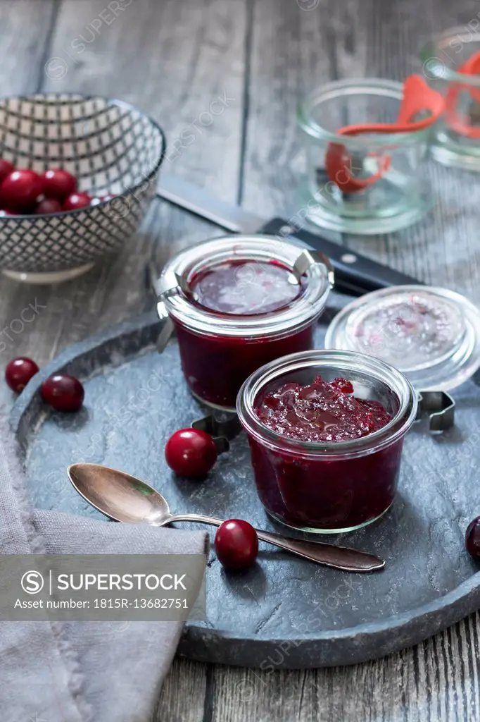 Preserving glasses of cranberry jam and fresh cranberries