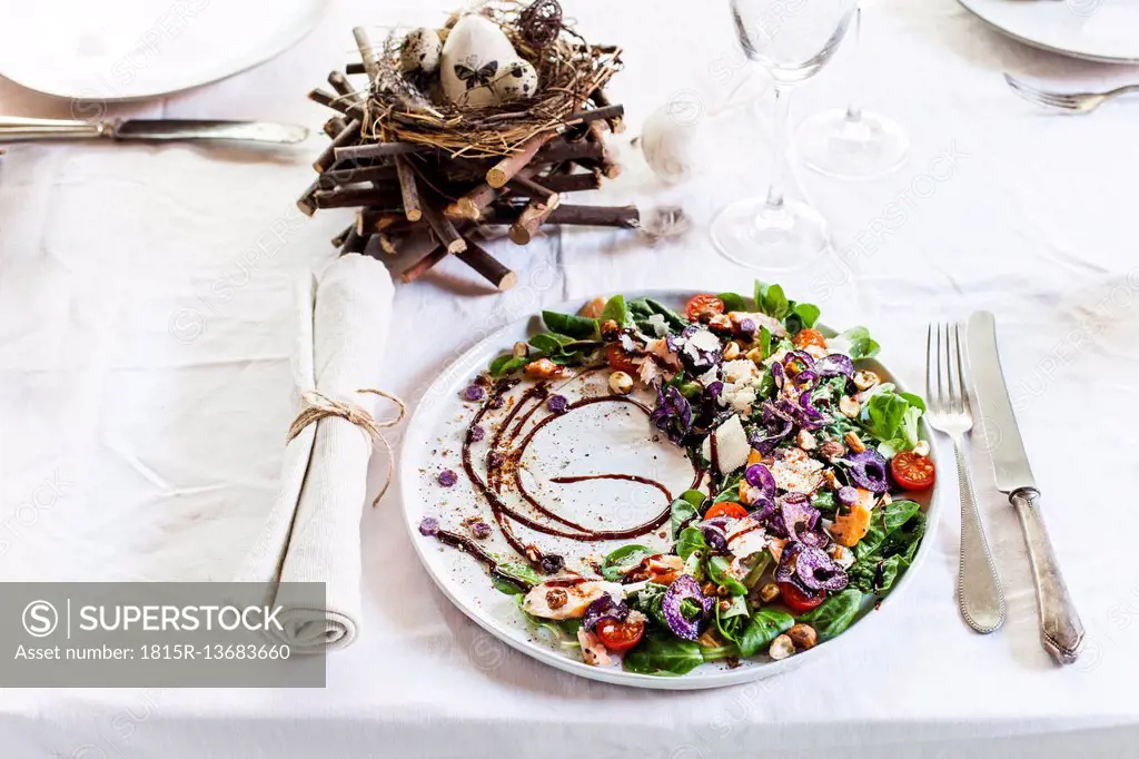 Colourful salad plate with smoked salmon, Crema di Balsamico and hazelnut oil on laid table