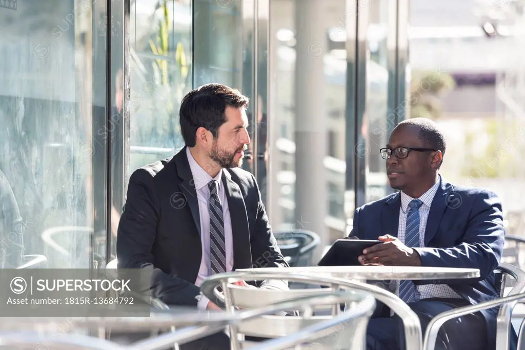 Two businessmen at outdoor cafe with tablet