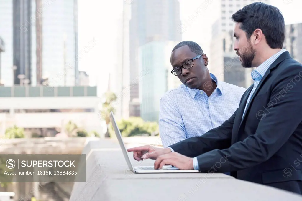 Two businessmen using laptop together