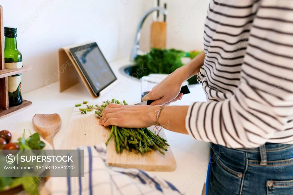 Young woman cooking at home using digital tablet for recipe