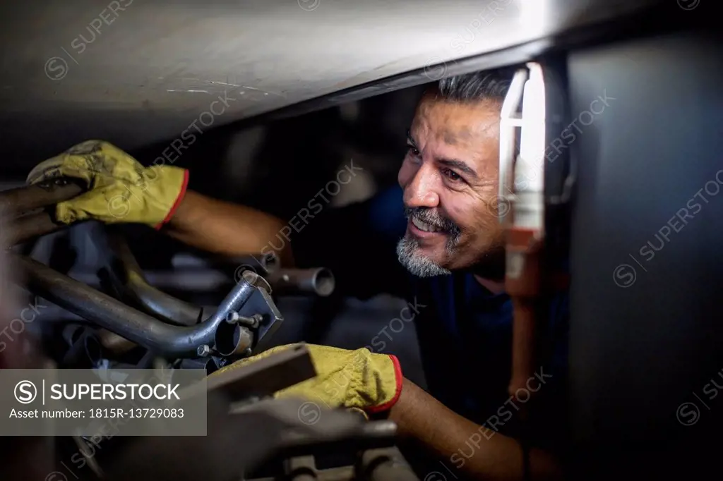 Smiling mechanic working on motorcycle in workshop