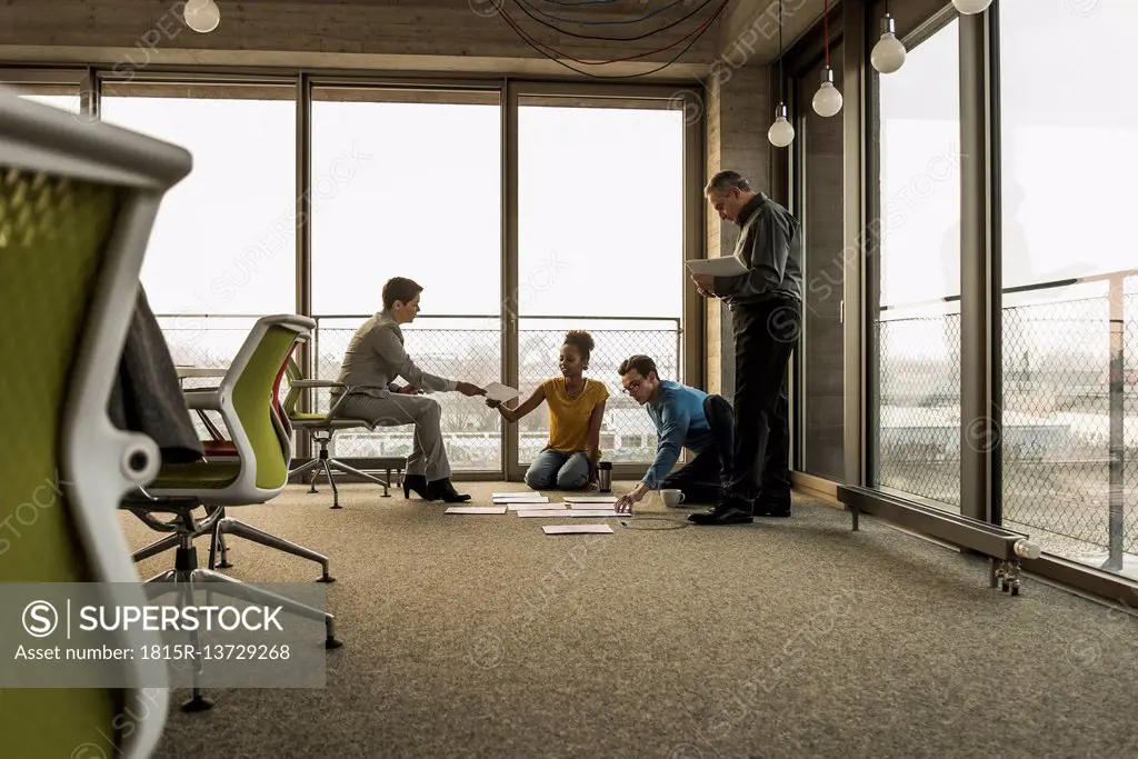 Businesspeople looking at documents on office floor