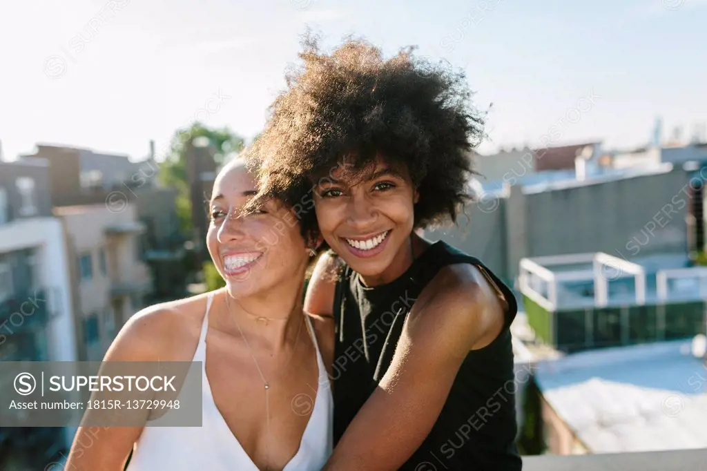 Female friends standing on rooftop, embracing