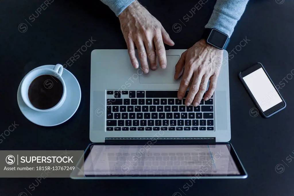 Top view of businessman at desk with laptop, smartphone and cup of coffee