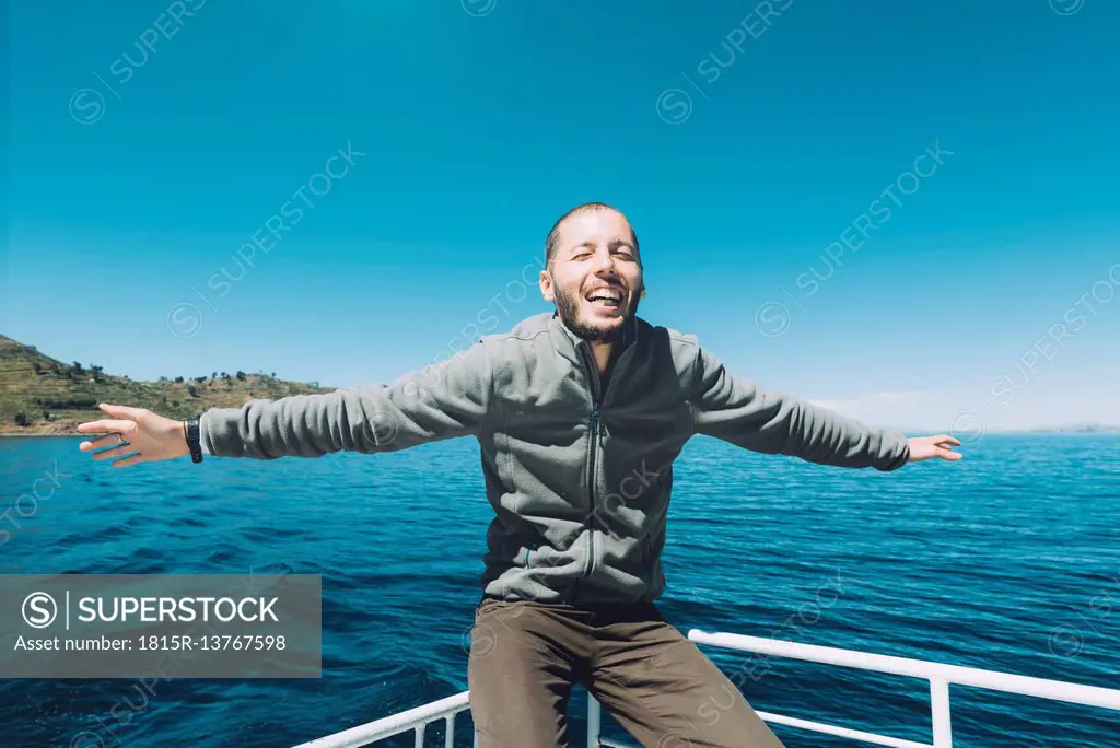 Peru, Titicaca lake, Taquile, happy man with outstretched arms on a boat