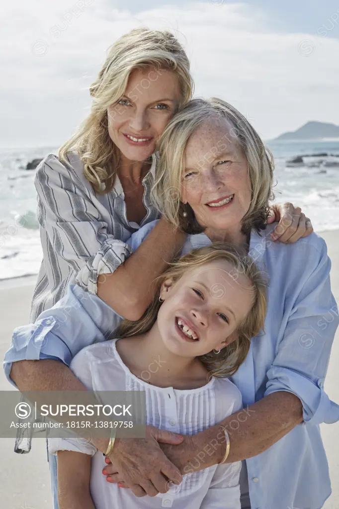 Mother, daughter and grandmother embracing on the beach