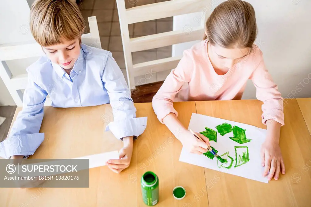 Brother and sister painting recycling symbols