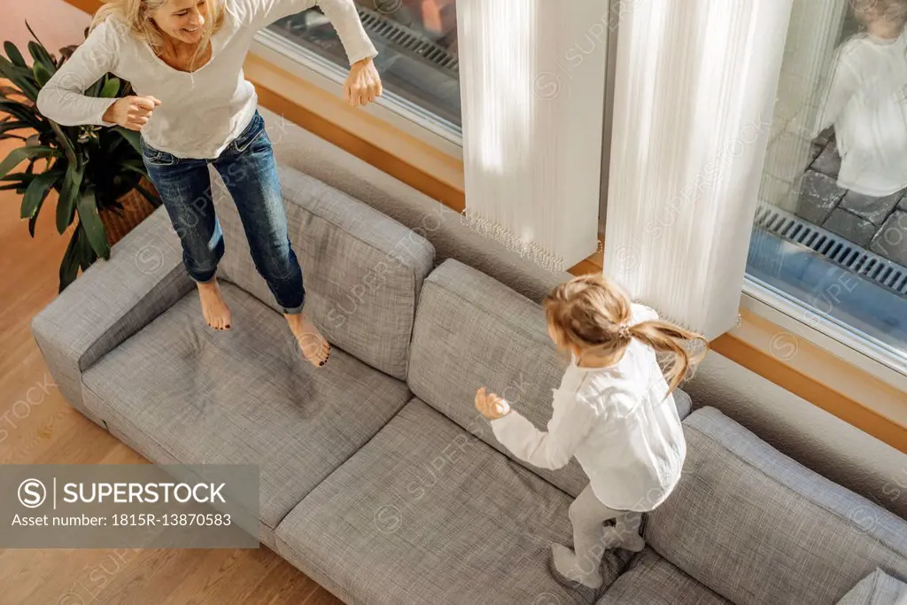 Mature woman and girl at home bouncing on couch