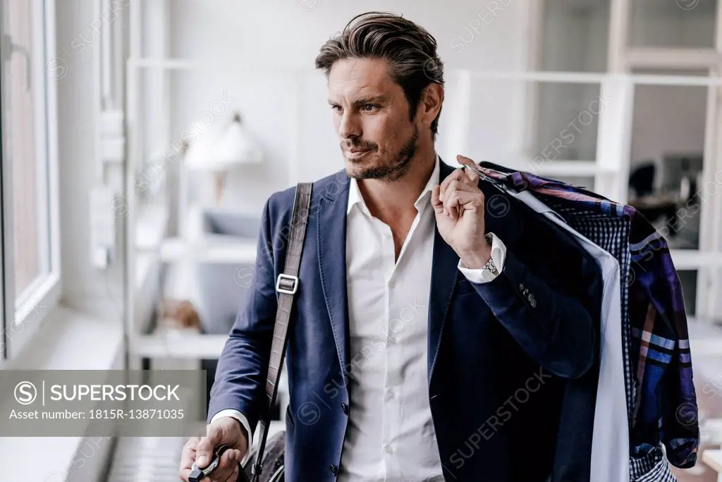 Serious businessman carrying clothes