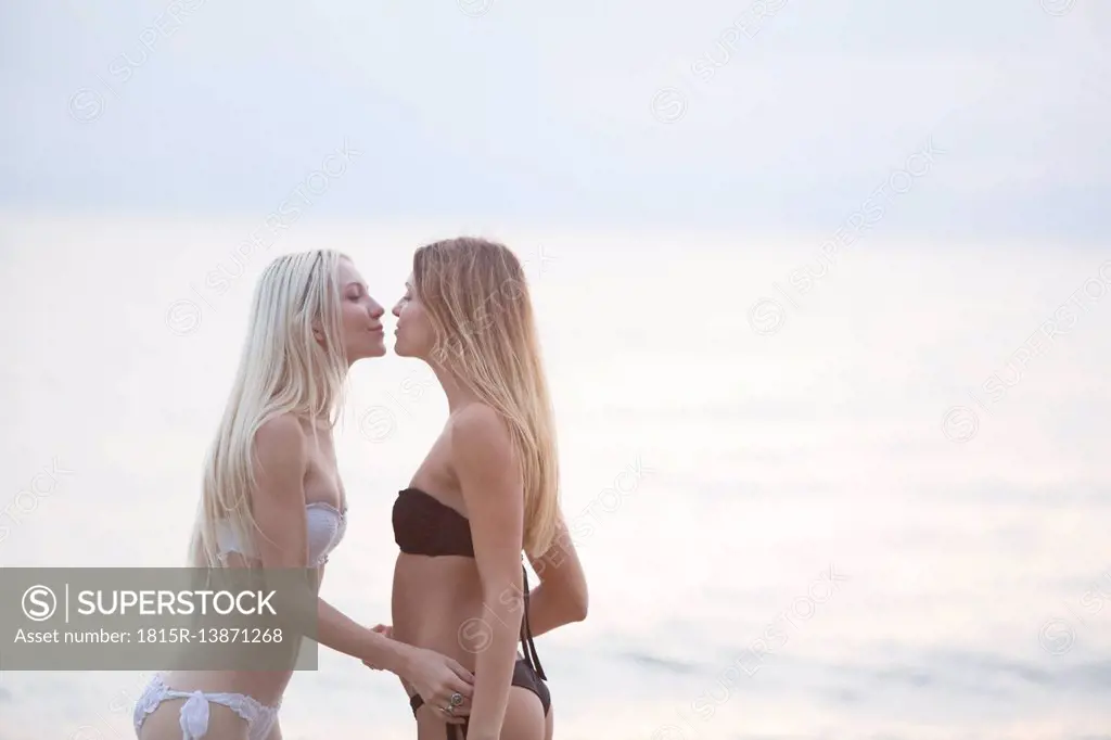 Two young women kissing at the sea