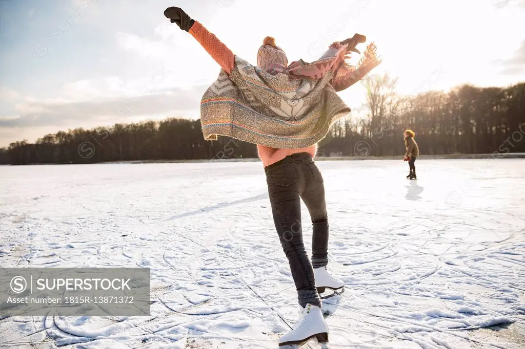 Rear view of woman with ice skates on frozen lake