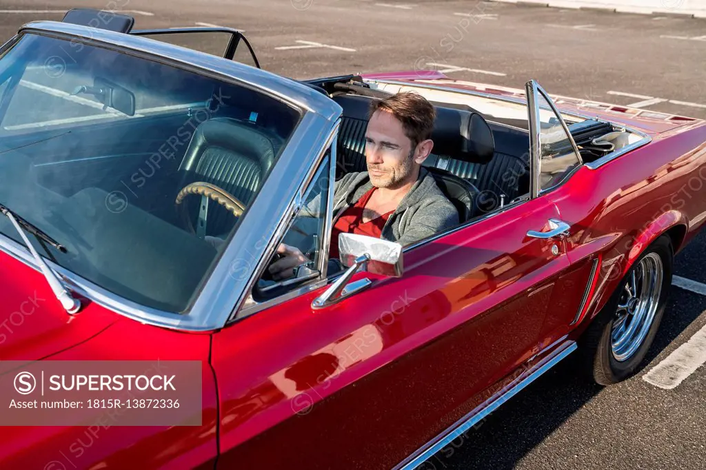 Mature man sitting in his red sports car