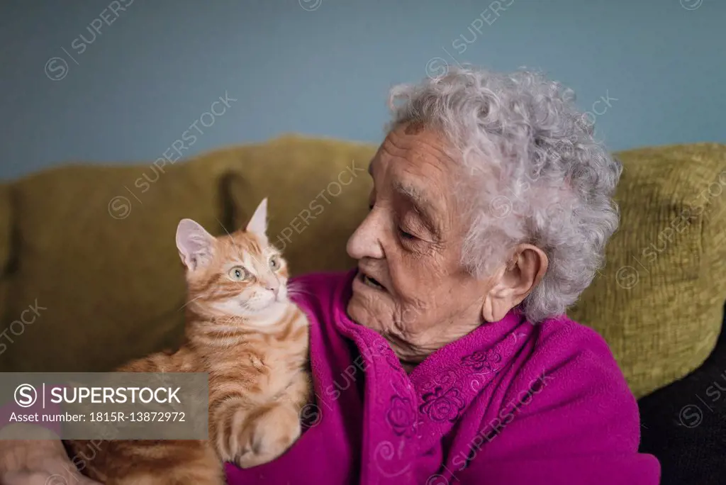 Senior woman sitting with tabby cat on the couch