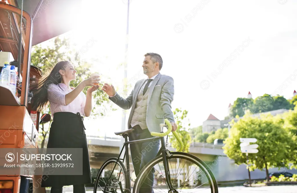 Businessman with bicycle buying take away coffee on the street