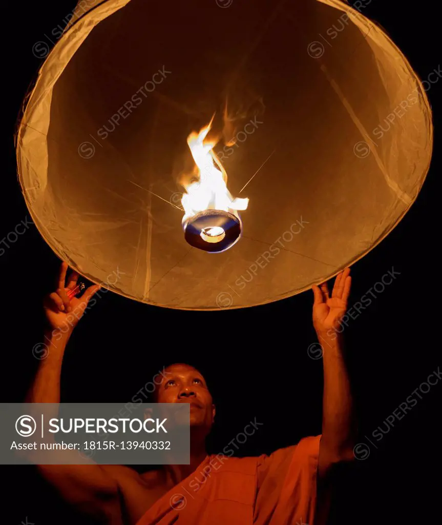 Thailand, Chiang Mai, Buddhist monk lighting lantern