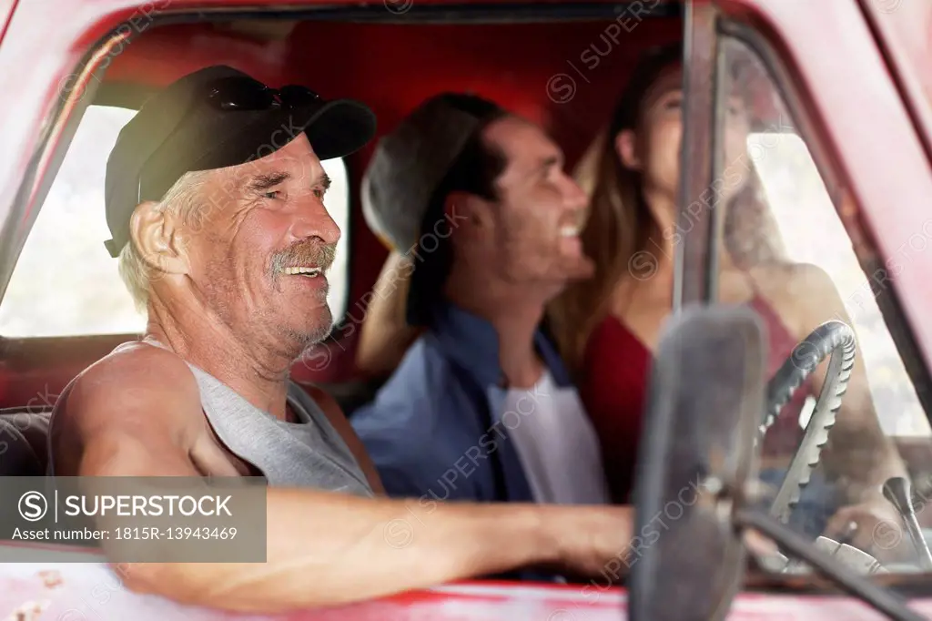 Happy senior man and young couple in an old pick up