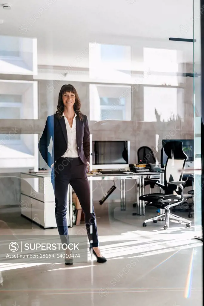 Successful businesswoman standing in office with hands in pockets