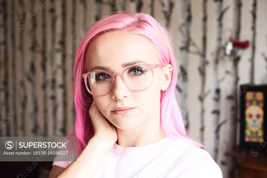 Portrait of young woman with pink hair, glasses and piercings