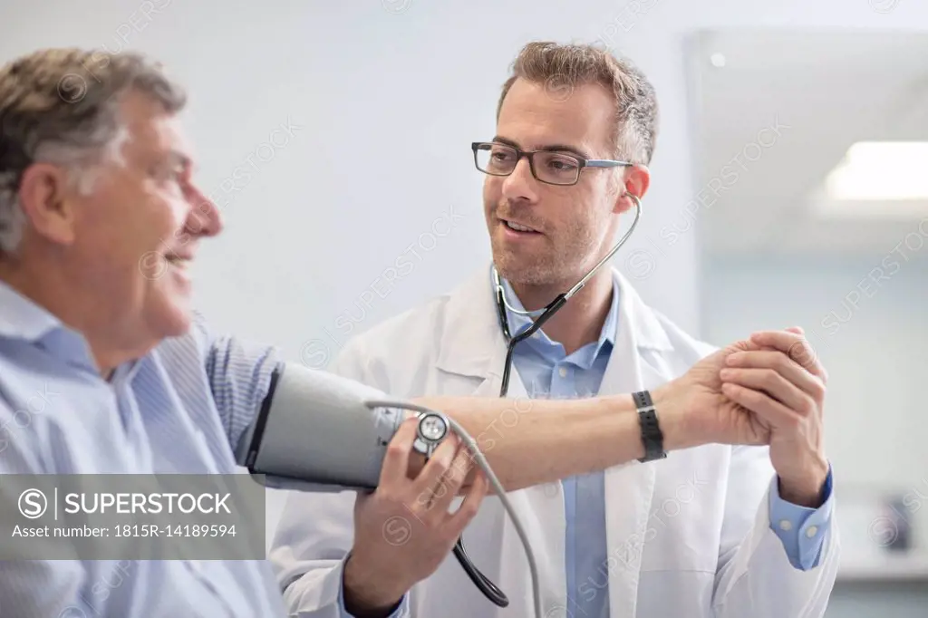 Doctor taking blood pressure of senior patient in medical practice