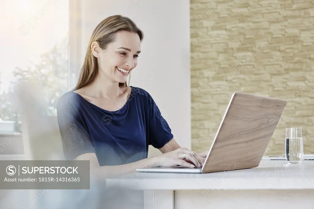 Happy woman at home using laptop