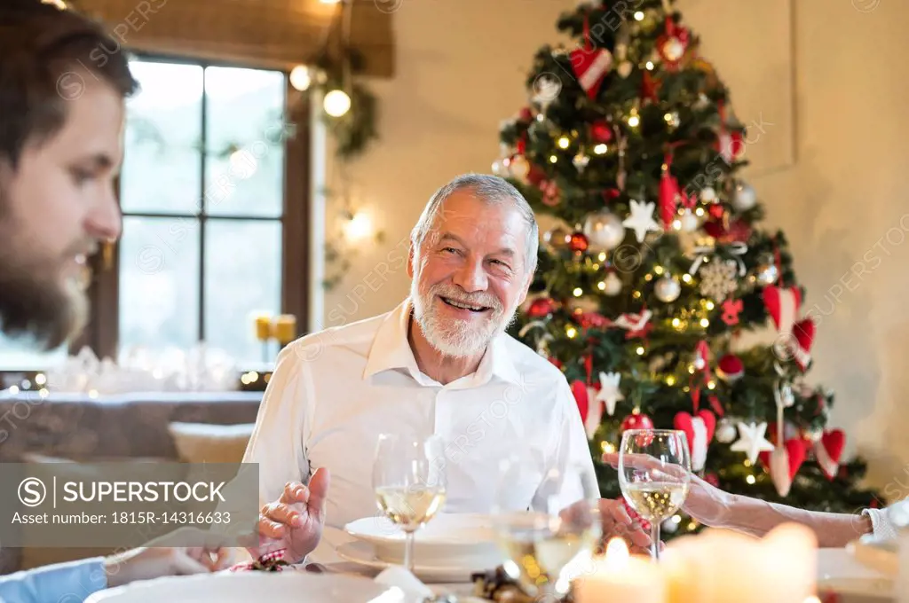 Smiling senior man looking at adult son at Christmas dinner table