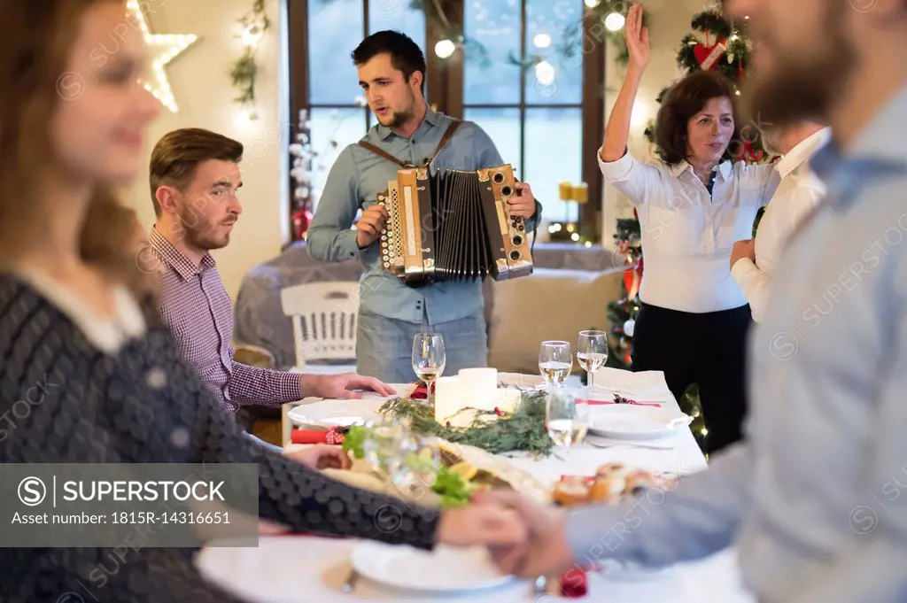 Young man playing accordion for family at Christmas