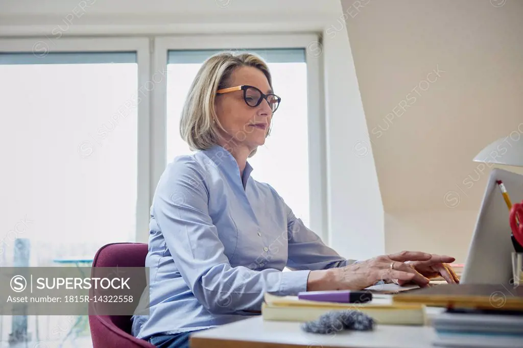 Mature woman at home using laptop at desk