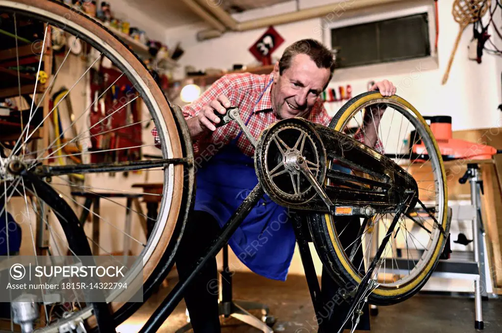 Senior man checking bicycle in his workshop