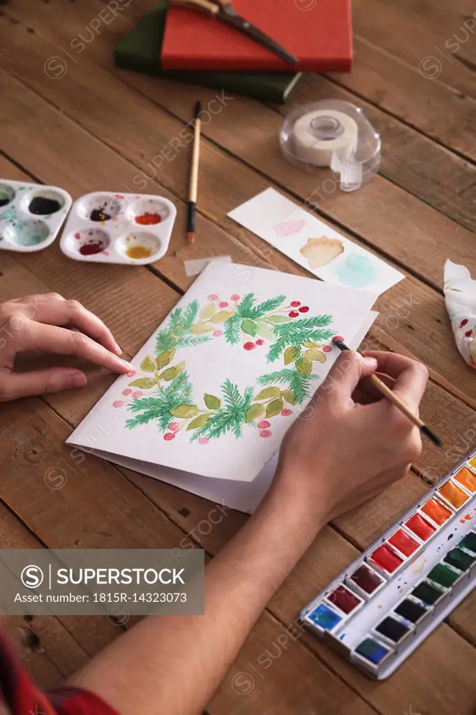 Young woman painting Christmas card with water colors, close-up