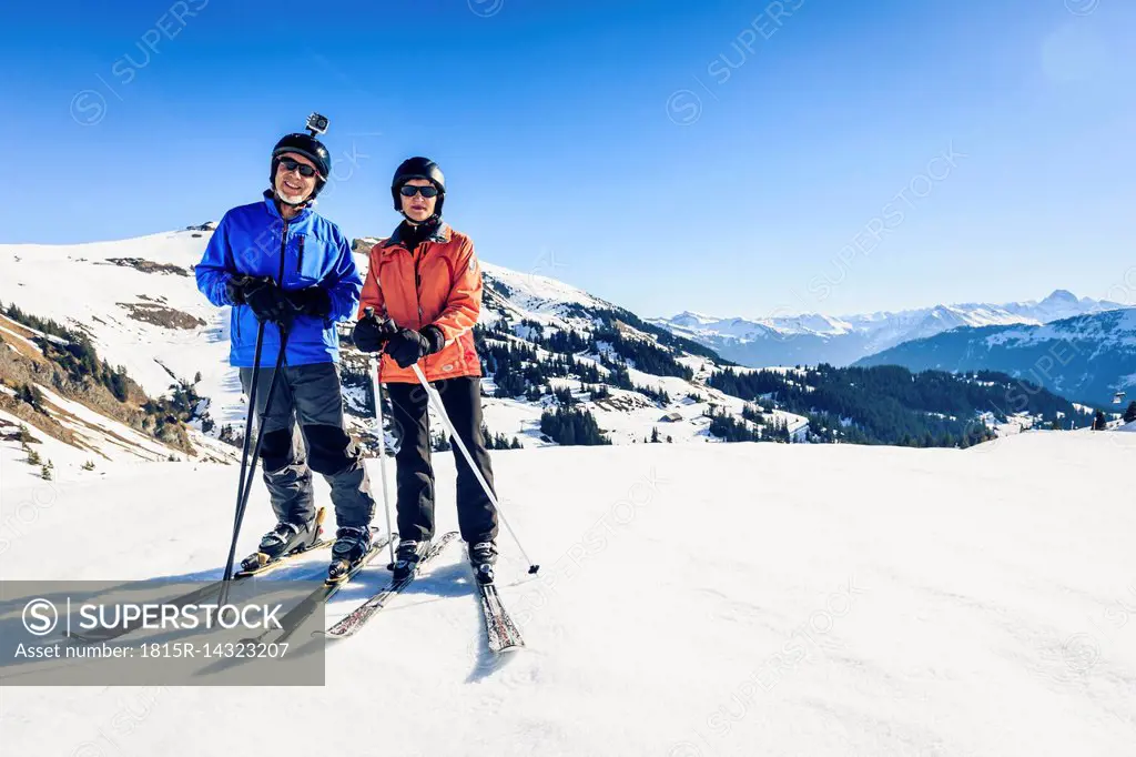 Austria, Damuels, couple with action cam skiing in winter landscape