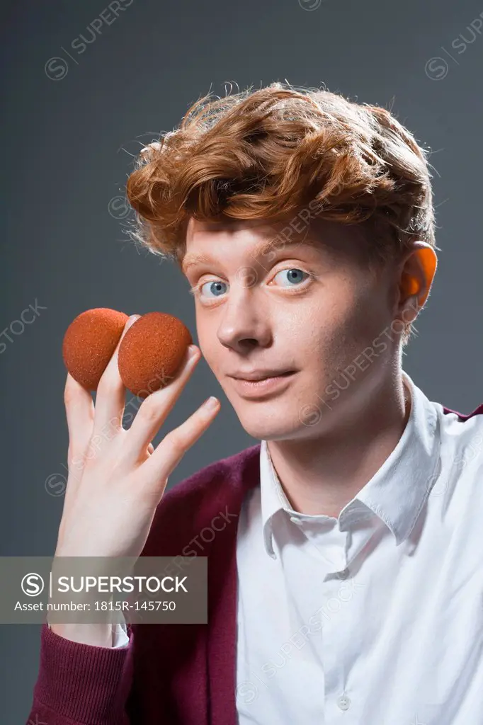 Portrait of young man holding balls, close up