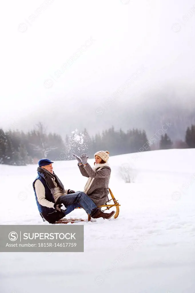 Senior couple with sledge having fun in snow-covered landscape