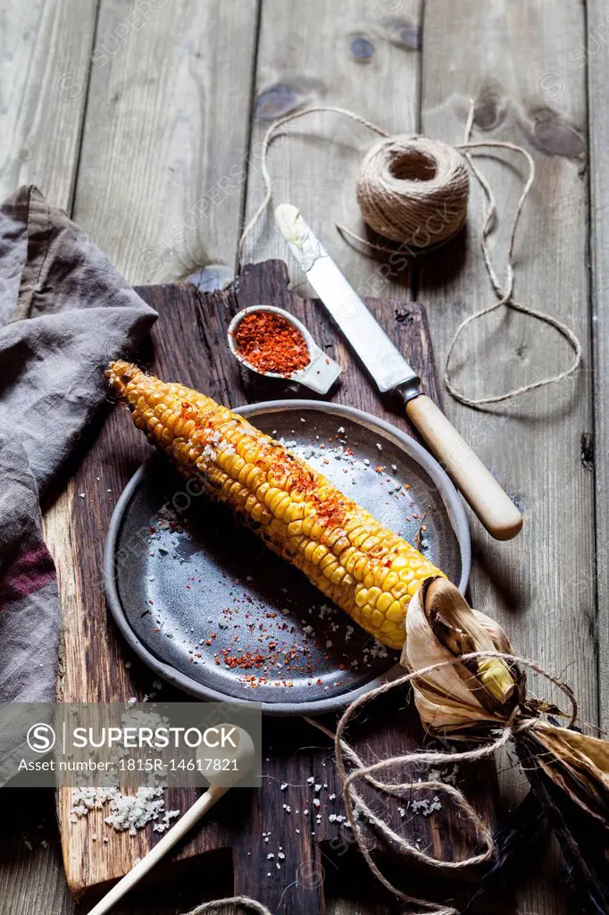 Grilled corncob with butter, salt and chili flakes on plate